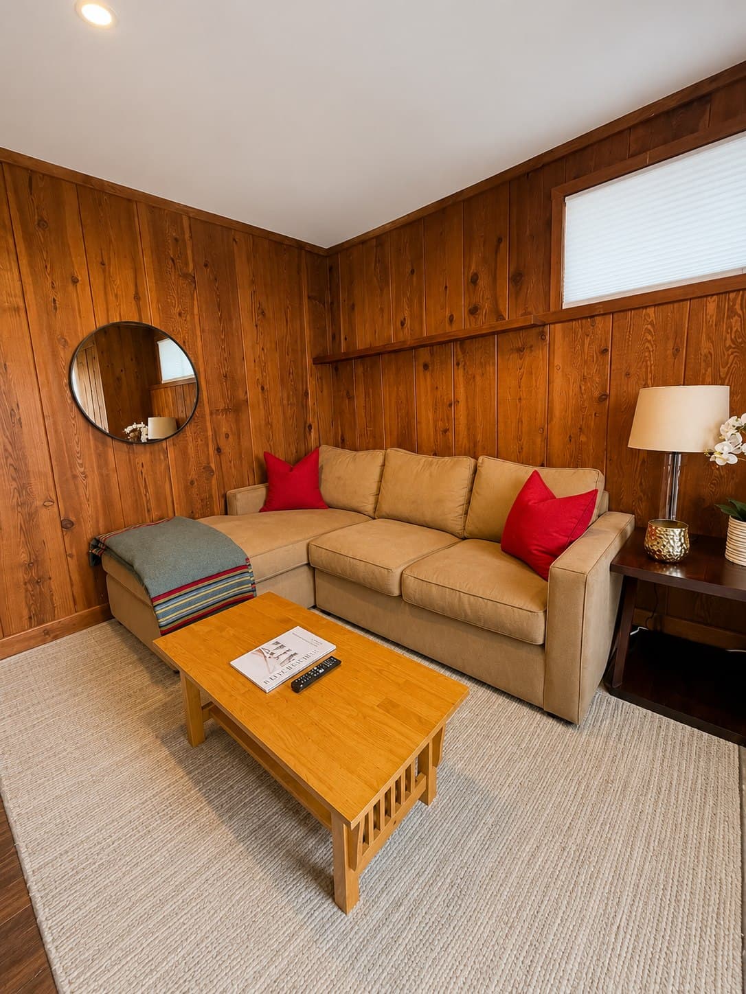 Cozy wood-panelled living room with a tidy sectional sofa and rug after a ShinySpaces residential cleaning